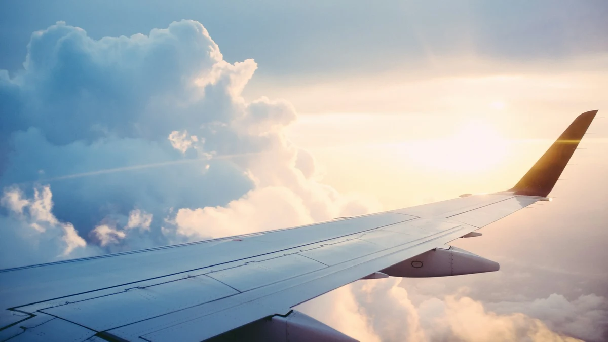 Airplane wing soaring over clouds at sunset showcasing reliable inflight connectivity